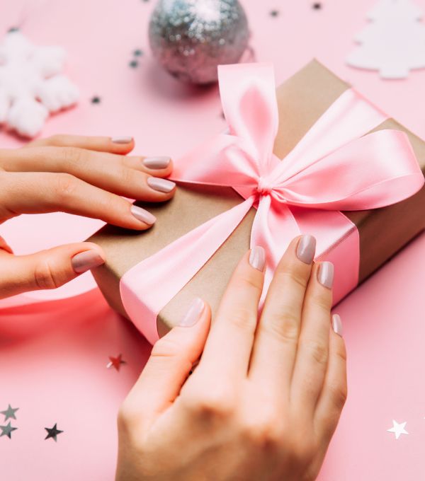 Hands holding pink wrapped gift with bow